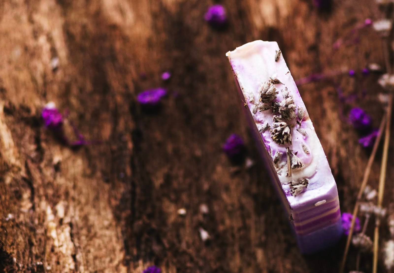 „Детайлна снимка на ръчно изработен натурален сапун Лавандула 100 г с лавандулови цветове посипани върху него“